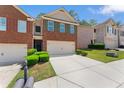 View of a traditional brick townhome featuring a two-car garage and a neatly landscaped front yard at 2714 Haynescrest Dr, Grayson, GA 30017