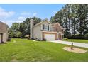 View of the home's side yard with ample green space, mature trees, and brick detailing at 1900 Green Oak Cir, Lawrenceville, GA 30043