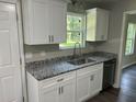 Functional kitchen featuring granite counters, white cabinets, and a stainless steel dishwasher at 433 Rhett Dr, Loganville, GA 30052