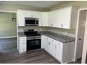 Modern kitchen featuring white cabinets, granite countertops, and stainless steel appliances at 433 Rhett Dr, Loganville, GA 30052