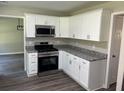 Modern kitchen with white cabinets, granite countertops, and stainless steel appliances at 433 Rhett Dr, Loganville, GA 30052