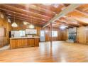 Open-concept living room with wood-paneled walls and wood floors flows to kitchen with breakfast bar and fireplace at 504 N Little Victoria Rd, Woodstock, GA 30189