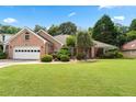 Inviting brick home with a two-car garage, manicured landscaping, and mature trees under a sunny sky at 1297 Hadaway Trl, Lawrenceville, GA 30043