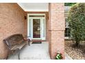 Charming covered front porch with brick accents, a bench, and a beautifully adorned entrance door at 1297 Hadaway Trl, Lawrenceville, GA 30043