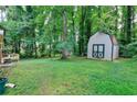 Expansive, tree-lined backyard with lush lawn, storage shed and bordered by mature trees at 2802 Leisure Woods Ln, Decatur, GA 30034
