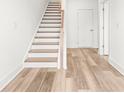 Bright hallway featuring light wood floors, white trim, and a staircase with wooden handrail at 490 Hammons Way, Atlanta, GA 30315