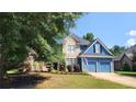 Beautiful two-story home featuring blue siding, stone accents, a manicured lawn, and an attached garage at 29 Sedgefield Overlook, Dallas, GA 30157