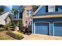 Close-up of a charming home, showcasing a stone facade, landscaped garden, and a two-car blue garage at 29 Sedgefield Overlook, Dallas, GA 30157