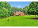 Beautiful two-story red brick home surrounded by lush greenery and an open front lawn at 2071 Habersham Cir, Covington, GA 30014