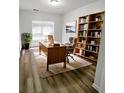 Well-lit home office with built-in bookshelves, wood desk, comfortable chair, and modern decor at 5050 Roxton Ln, Douglasville, GA 30135