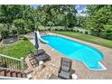 An elevated view of a beautiful backyard pool with lounge chairs, an umbrella, and landscaped greenery at 522 Golfview Dr, Peachtree City, GA 30269