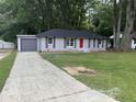 Exterior view of a brick home with a driveway and a detached garage showing the yard and mature trees at 8236 Tudor Dr, Jonesboro, GA 30238