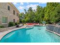 Luxurious outdoor pool area featuring a waterfall feature, sun loungers, and verdant landscaping at 11140 W Rd, Roswell, GA 30075