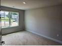 Bedroom with neutral walls and trim, a large window overlooking the neighborhood, and an electrical outlet at 305 Melanie Ct, Bowdon, GA 30108