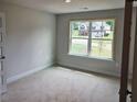 Bedroom with natural light, neutral walls and trim, and a large window overlooking the neighborhood at 305 Melanie Ct, Bowdon, GA 30108