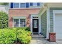Close-up of the front entrance featuring a black door, brick accents, and lush green bushes at 335 Pintail Ct, Suwanee, GA 30024