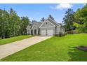 Exterior view of home with a two-car garage, well-maintained lawn, and a covered front porch at 287 Flower Farm Dr, Acworth, GA 30101