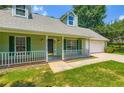 Inviting front porch with white railings, green siding, and a convenient attached two-car garage at 230 Belmont Trl, Covington, GA 30016
