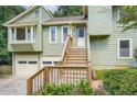 Green home with a two-car garage, wooden stairs leading to the front door, and manicured landscaping at 5093 Ravenwood Dr, Marietta, GA 30066
