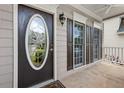 Close-up of a home's front porch with an oval glass front door and paneled windows with dark shutters at 507 Mirramont Pl, Woodstock, GA 30189
