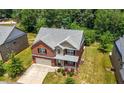 Aerial view of a two-story brick home, showcasing the well-manicured lawn, and mature trees in a quiet neighborhood at 2445 Whitehead Place Dr, Suwanee, GA 30024