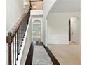 Bright foyer featuring hardwood floors, staircase with iron railing, arched doorways, and neutral color palette at 2445 Whitehead Place Dr, Suwanee, GA 30024