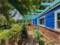 Cozy side entrance with a turquoise pergola adorned with greenery leading to the brick entryway at 5130 Dearing St, Covington, GA 30014