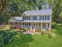 Beautiful two-story home with a classic brick facade, a cozy front porch, and a lush green lawn surrounded by trees at 3835 Thornhill Sw Dr, Lilburn, GA 30047