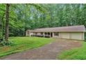 Ranch-style home with well-maintained lawn, mature trees, and attached two-car garage at 7704 Holyoke Rd, Cumming, GA 30040