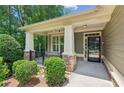 Inviting front porch features stone supports, white columns, black railing and a glass front door at 328 Shade Tree Cir, Woodstock, GA 30188