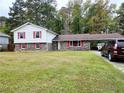 Split-level home featuring a large front yard, brick accents, red shutters, and a convenient carport at 7437 Grayson Dr, Riverdale, GA 30296