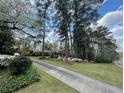 Landscaped front yard with long driveway to brick home amongst mature trees on sunny day at 1534 Cooper Lake Se Rd, Smyrna, GA 30082