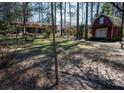 Large backyard with a small red storage shed or outbuilding, surrounded by mature trees at 1288 Skyview Sw Cir, Mableton, GA 30126