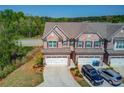 Brick townhome featuring a two-car garage, driveway, and manicured lawn in a serene setting at 2378 Morgan Creek Rd, Buford, GA 30519