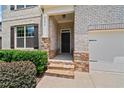 Inviting front entrance with brick and stone accents, black front door and manicured bushes at 2090 Beckham St, Cumming, GA 30041
