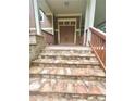 Close-up of the house's stone steps leading to the covered porch with a wooden railing and double door entrance at 2961 River Ridge Drive Sw, Atlanta, GA 30354