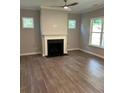Cozy living room with a fireplace, large windows providing natural light, hardwood floors, and modern ceiling fan at 3032 Farm Tract Trl, Woodstock, GA 30189