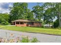 Attractive single-story brick house with a covered porch and a large, green front lawn and mature trees at 3888 Lindley Cir, Powder Springs, GA 30127