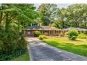 Charming brick home with well-manicured lawn, mature trees, and long driveway at 2343 Hunting Valley Dr, Decatur, GA 30033