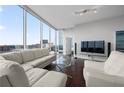 Cozy living room with large windows offering city views, a plush white sofa set, and hardwood floors, ideal for relaxation at 1080 Peachtree Ne St # 2710, Atlanta, GA 30309