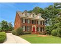 Elegant brick home featuring lush landscaping and a driveway leading to a red front door at 4045 Boles Creek Dr, Duluth, GA 30096
