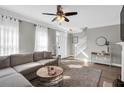 Bright living room featuring a comfortable sofa, large windows with sheer curtains, and modern decor at 5990 Eagle Tiff Ln, Sugar Hill, GA 30518