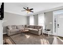 Spacious living room with a large sectional sofa, modern ceiling fan, and bright natural light at 5990 Eagle Tiff Ln, Sugar Hill, GA 30518