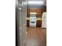 Kitchen featuring wood cabinets, laminate countertops, white appliances, and wood look flooring at 6470 Bedford Ln, Lithonia, GA 30058