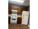 Kitchen featuring wood cabinets, laminate countertops, white appliances, and wood look flooring at 6470 Bedford Ln, Lithonia, GA 30058