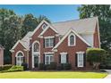 Charming two-story brick home with landscaped yard, manicured shrubbery, and welcoming front entrance on a sunny day at 325 Stonecastle Sw Pass, Atlanta, GA 30331