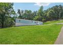 Bright, grassy lawn slopes down to a light blue single-story home with white foundation and gravel driveway at 4820 Scott Rd, Cumming, GA 30041