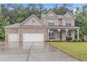 Two-story brick home with three-car garage, and front porch at 6179 Ashbranch Dr, Acworth, GA 30101