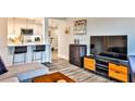 Open-concept living space featuring a kitchen with white cabinets, bar seating and media center with flatscreen TV at 1 Biscayne Drive Nw # 706, Atlanta, GA 30309