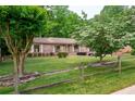Well-maintained home with lush green lawn, mature trees, and a rustic split rail fence in the front yard at 655 Stone Harbor Sw Pkwy, Marietta, GA 30060
